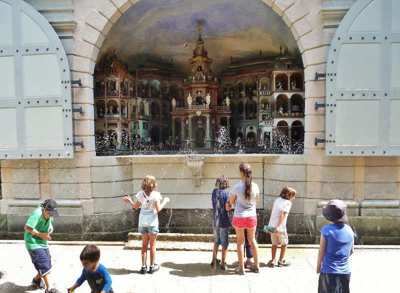 Children getting squirted by trick fountains all around them